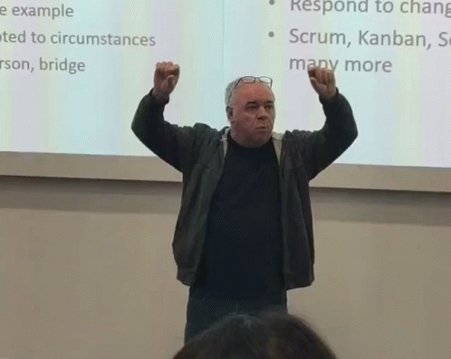 a man is holding his fist up while standing in front of a projection screen