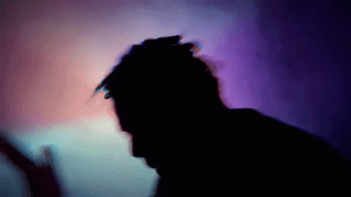 the silhouette of a man in front of a purple wall