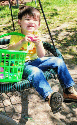 a little boy sitting on top of a green basket
