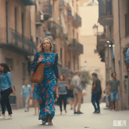 a woman in a long dress walks down a street