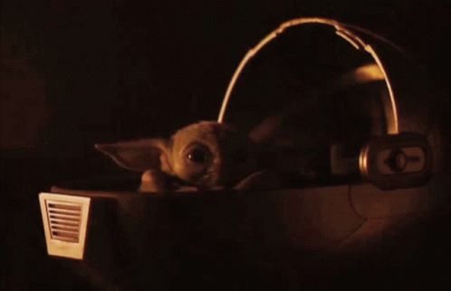 a baby yoda in the dark with headphones