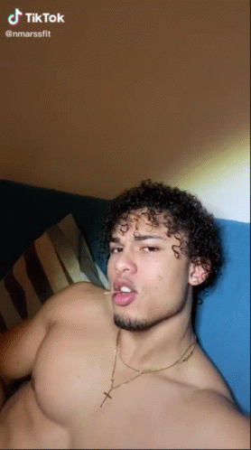 a man with curly hair and piercings in a bed