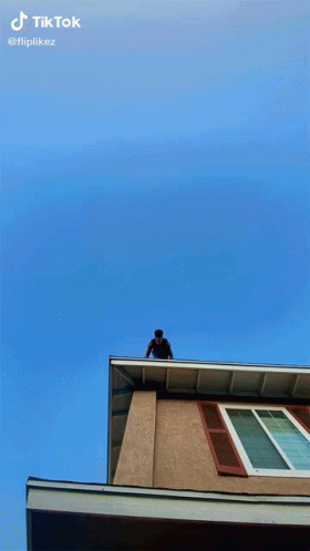 a guy sitting on top of a tall building