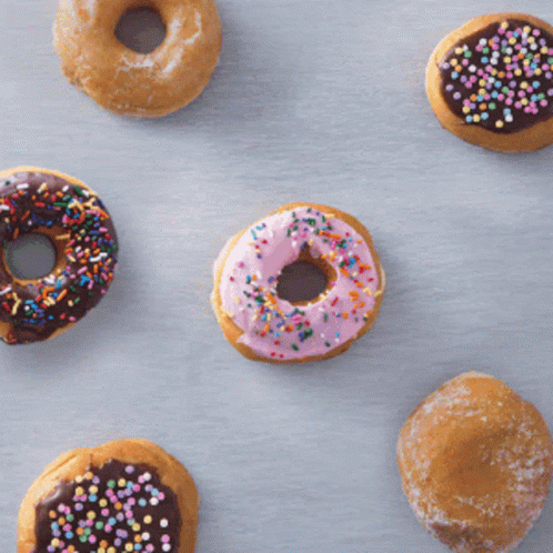 nine different donuts with frosting and colorful sprinkles