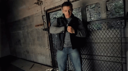 a man standing outside in a  cell with his finger out and wearing a leather jacket