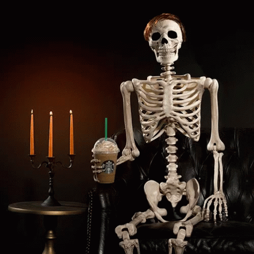skeleton sitting on a couch with a blue candle
