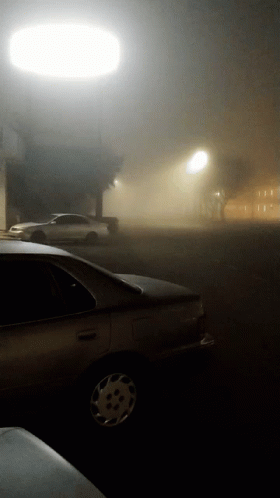 there is a car driving down a foggy street