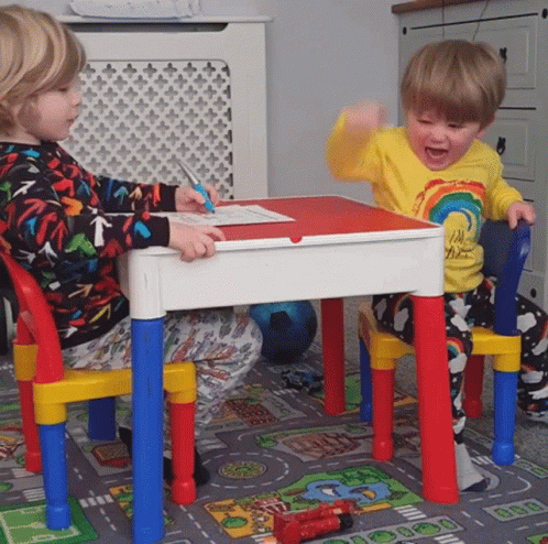 two small children are playing with a toy table and chairs