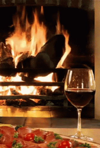 blue flames glow on the fireplace with a glass of wine