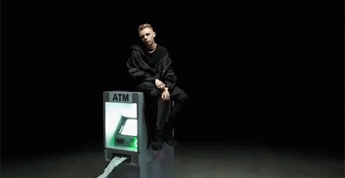 the man sits on top of a green electronic sign