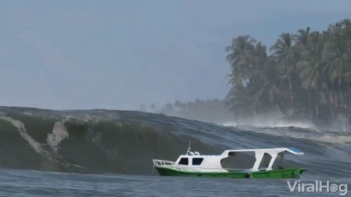 a boat sitting in the water near a large wave