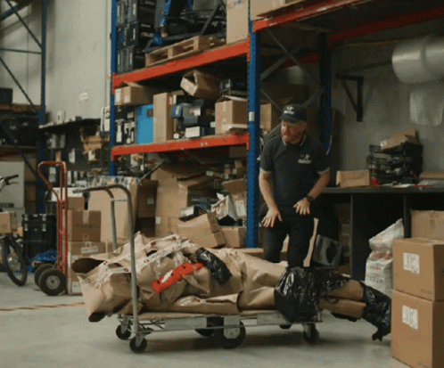 an employee hing a cart of packages with his face to the ceiling