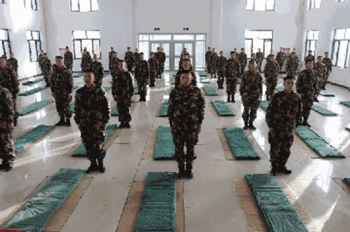 soldiers walk through large rows of sleeping mats on their backs