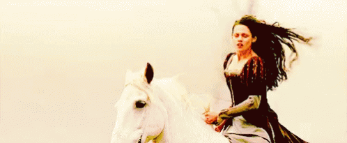 a girl riding a white horse with a man holding on to her