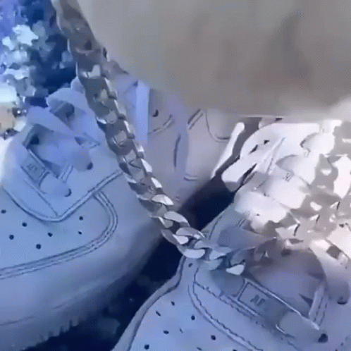 two white sneakers with chains hanging out of them