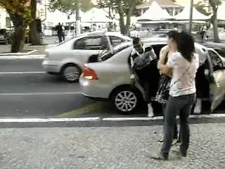 a woman holding a purse walks past a group of cars