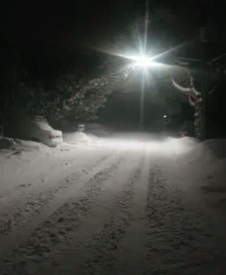 a car driving down a snow covered road at night