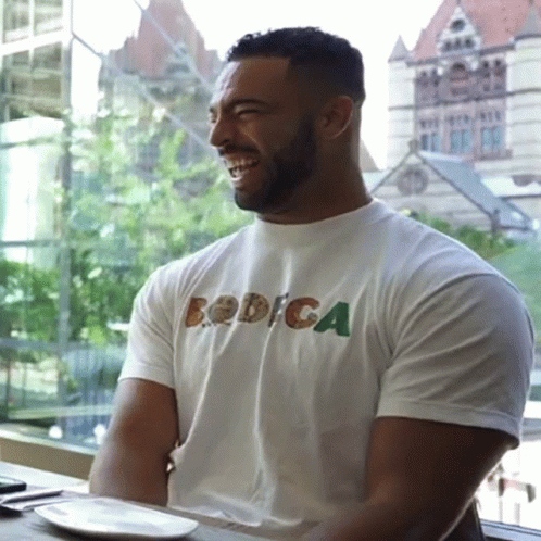 a man sitting at a table while wearing a t - shirt that says robiga on the side
