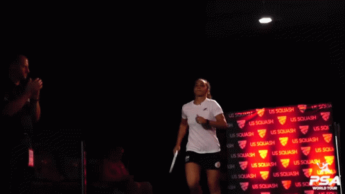 a tennis player in blue is walking in front of a black backdrop