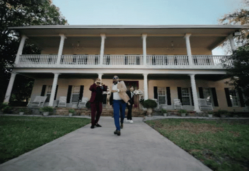 two men standing in front of a big house
