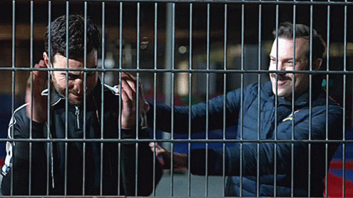 two people with blue makeup behind bars in a building