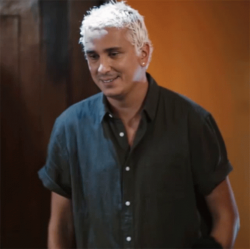 a man with white hair smiles for a camera