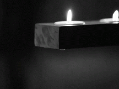 two candles lit in an open dark room