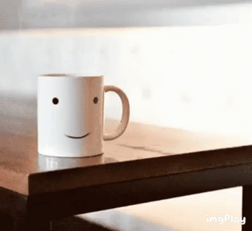 a ceramic cup sitting on a table with a smiley face