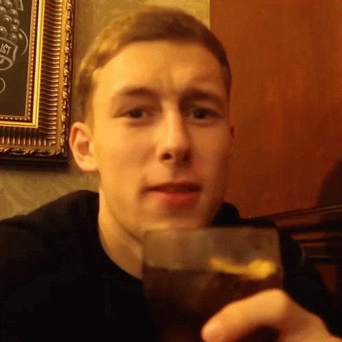 young man drinking glass in the dark with dark blue walls