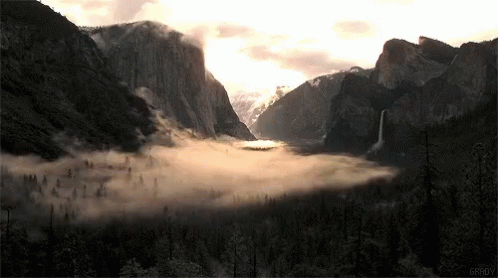 an icy river surrounded by mountains with fog