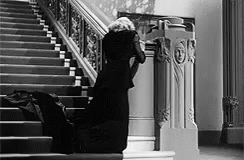 a woman in black and white standing at the top of a set of stairs