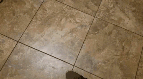 a person standing on a tile floor with shoes on it