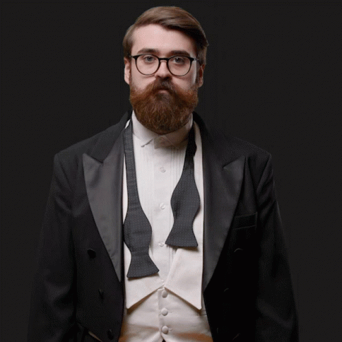 a bearded man wearing glasses and a jacket