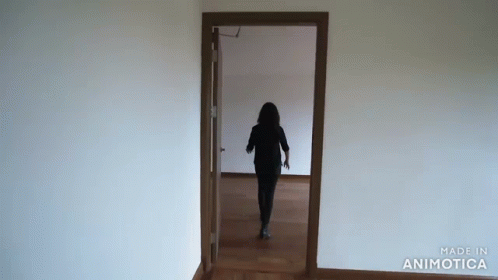 a person walking down a hallway through a door way