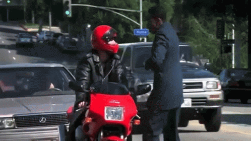 a man in a dark outfit is standing next to his motorcycle