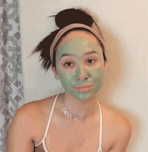 a woman with a green face mask on is standing up