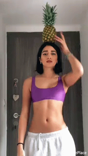 a woman in a bikini is standing under a pineapple