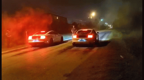 two police cars traveling down a city road at night