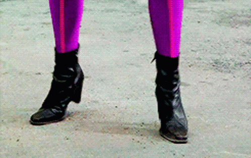 a woman in purple riding breeks and boots holds her purse