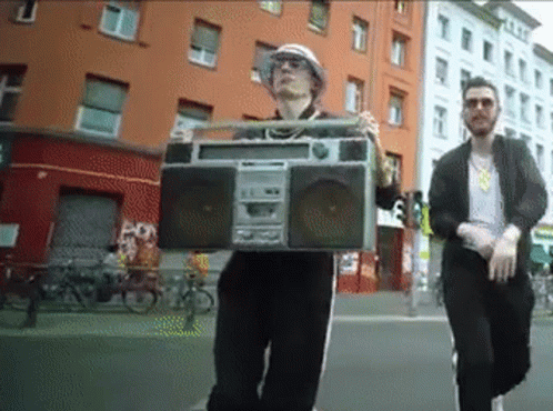 two men standing on the sidewalk with a boombox