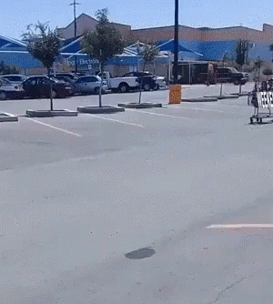 two people skateboarding down an empty parking lot