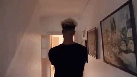 a person with white hair is seen walking down a hallway