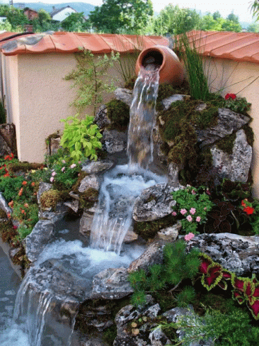 a small waterfall and pool surrounded by plants