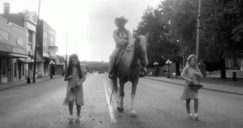 two girls are walking down the street on their horses