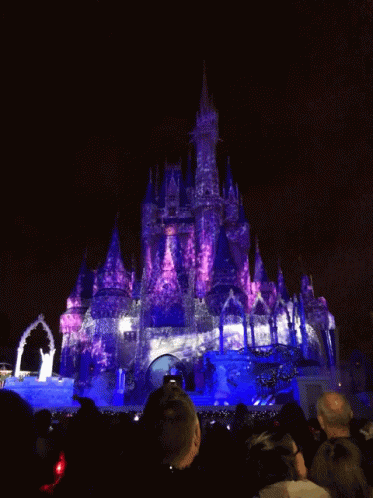 a large castle is lit up with colorful lights