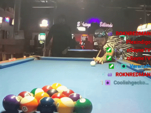 a pool table with pool balls and a man standing behind