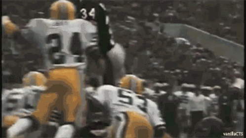 two football players are high in the air above a crowd