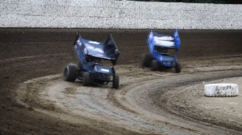 two trucks that are driving on the dirt