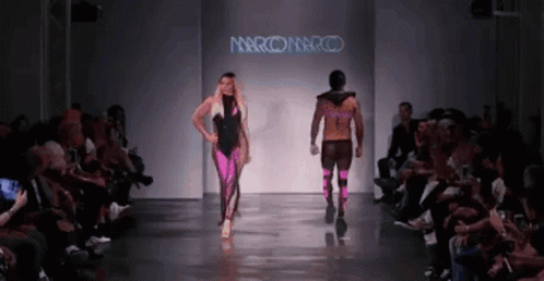 two models on runway wearing clothing with people watching