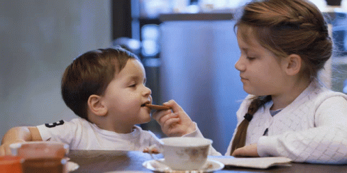 two children sitting at a table eating food